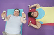 Photo: Overweight man and woman lying down lifting dumbbells, overhead view Overweight man and woman lying down lifting dumbbells, overhead view