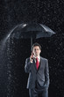 Businessman standing under sturdy Umbrella, hand in pocket