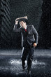 Businessman covering head with binder, running through rain