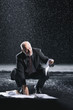 Businessman Picking up soaked Paperwork during downpour