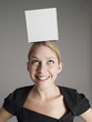 Young woman in black dress with white box on her head