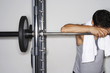 Sweaty man resting on barbell after workout