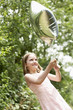 Girl in park playing in park with helium filled balloon