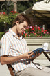 Photo: Young Man at Outdoor Cafe reading guidebook Young Man at Outdoor Cafe reading guidebook
