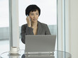 Businesswoman sitting at table with laptop, talking on phone