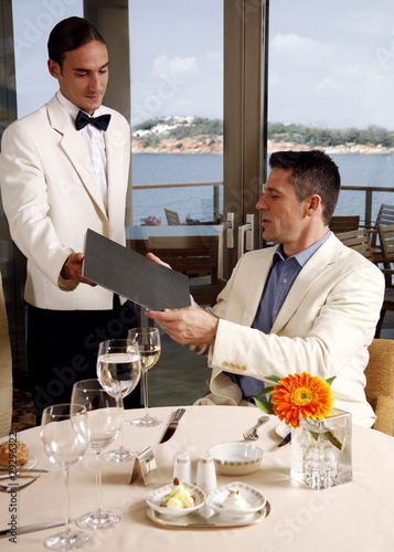 Photo: Waiter giving menu to customer in restaurant Waiter giving menu to customer in restaurant