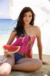 Young woman on beach with a watermelon slice