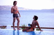 Two men with cocktails by the poolside