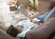 Man lying down on sofa in home with cardboard boxes