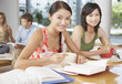 Young Woman eating bowl of noodles with chopsticks in cafeteria