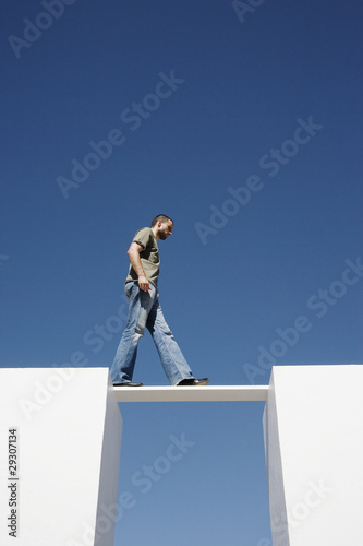 Photo: Man walking on board between two walls outdoors Man walking on board between two walls outdoors