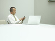 Businessman in office on mobile phone with laptop on table
