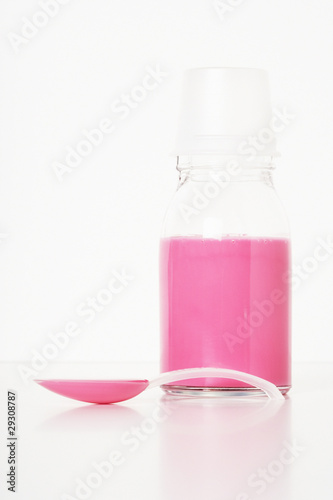Photo: A container of medicine with a spoonful in front of it A container of medicine with a spoonful in front of it