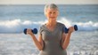 Elderly woman working his muscles with dumbbells