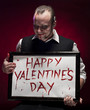 Photo: Man holding a happy valentine's sign written with blood. Man holding a happy valentine's sign written with blood.