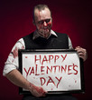 Foto: Man holding a happy valentine's sign written with blood. Man holding a happy valentine's sign written with blood.