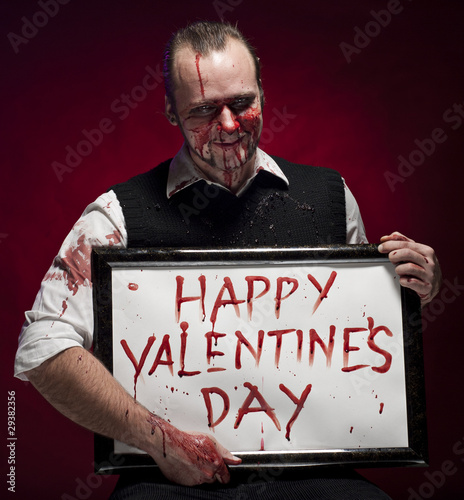 Photo: Man holding a happy valentine's sign written with blood. Man holding a happy valentine's sign written with blood.