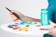 closeup of woman in blue shirt mixing paint on palette