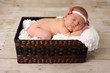Baby girl asleep in a basket.