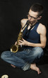 close-up  cross-legged young jazzman plays a saxophone