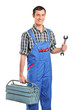 A repairman in blue overall holding a toolbox and wrench