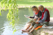 Großvater und Enkelin beim Zeitunglesen im Grünen am Teich
