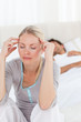 Photo: Attractive woman having a headache while her husband is sleeping Attractive woman having a headache while her husband is sleeping