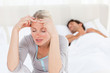 Photo: Attractive woman having a headache while her husband is sleeping Attractive woman having a headache while her husband is sleeping