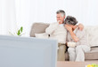 Mature couple watching tv in their living room Mature couple watching tv in their living room