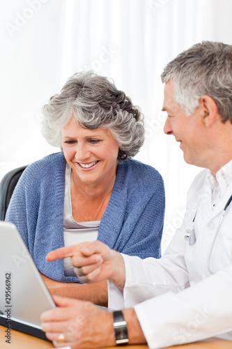 Photo: A senior doctor with his patient looking at the laptop A senior doctor with his patient looking at the laptop