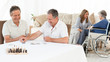 Photo: Men playing cards while their wifes are talking Men playing cards while their wifes are talking