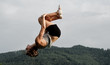female gymnast doing back somersault in nature female gymnast doing back somersault in nature