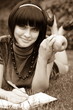 Young beautiful woman lays on green field with apple and book