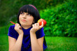 Young beautiful woman lays on green field with apple