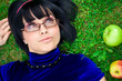 Young beautiful woman lays on green field with apple