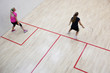 Two female squash players in fast action on a squash court (moti Two female squash players in fast action on a squash court (moti