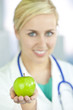 Smiling Woman Doctor in Hospital Holding Green Apple