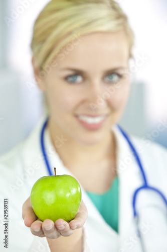 Photo: Smiling Woman Doctor in Hospital Holding Green Apple Smiling Woman Doctor in Hospital Holding Green Apple