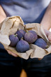 A man holding a paper bag containing fresh figs