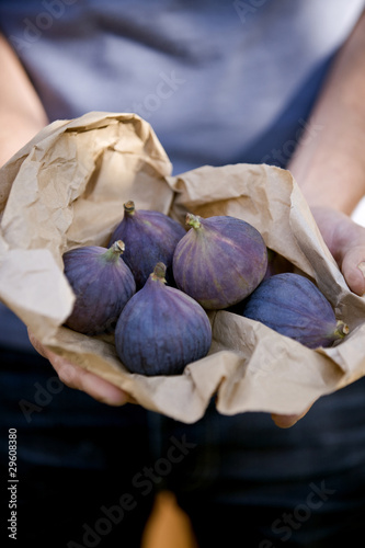 Photo: A man holding a paper bag containing fresh figs A man holding a paper bag containing fresh figs
