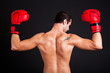 Back of a man with boxing gloves on dark background Back of a man with boxing gloves on dark background