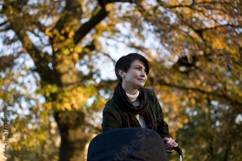 Photo: A mother standing with a buggy in the park A mother standing with a buggy in the park