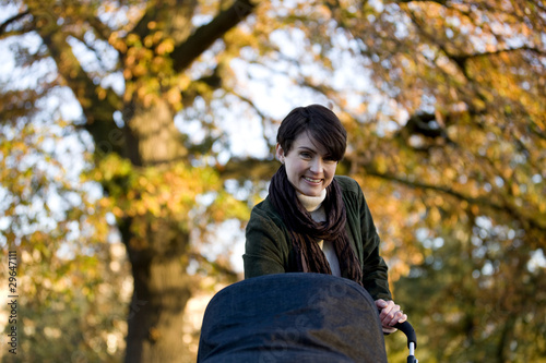 Photo: A mother standing with a buggy in the park A mother standing with a buggy in the park