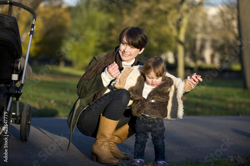 Photo: A mother helping her daughter stand in the park A mother helping her daughter stand in the park
