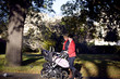 Two mothers pushing their buggies in the park, smiling