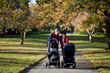 Two mothers looking at their babies in buggies in the park
