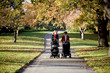 Two mothers pushing their buggies in the park, talking
