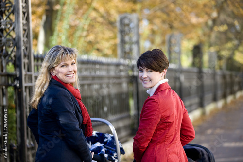 Photo: Two mothers standing with buggies in the street, smiling Two mothers standing with buggies in the street, smiling