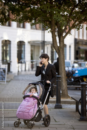 Photo: A mother standing with a buggy, talking on her mobile phone A mother standing with a buggy, talking on her mobile phone