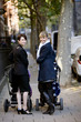 Two mothers standing with buggies in the street, smiling
